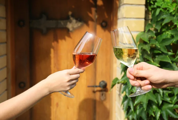 Handen met glazen met wijn op houten deur achtergrond — Stockfoto