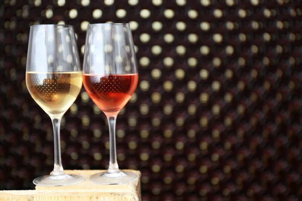 Glazen wijn op wazig fles muur achtergrond — Stockfoto