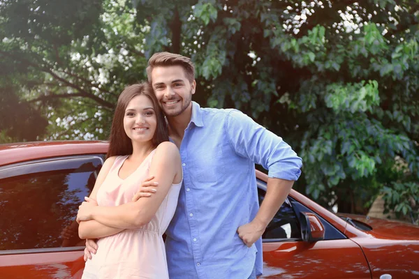 Młoda para piękny stojący w pobliżu czerwony samochód — Zdjęcie stockowe