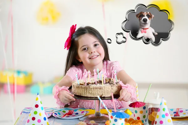 Happy little girl with tasty cake at birthday party dreaming about the dog