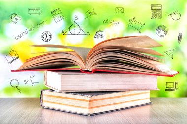 Ahşap masa üzerinde kitap yığını. Simgeleri yeşil arka plan bulanık. Bilgi kavramı.