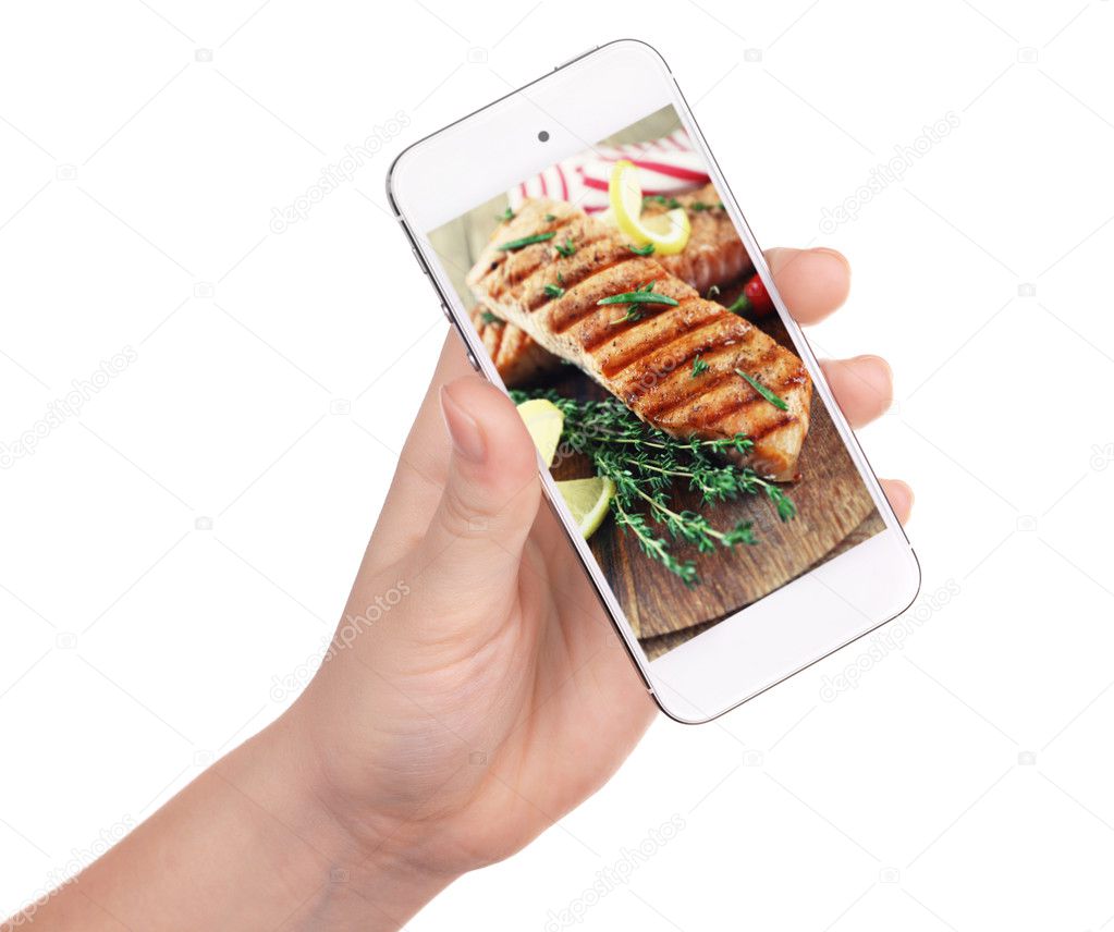 Female hand holding smartphone on white background. Photo of food on smartphone screen.