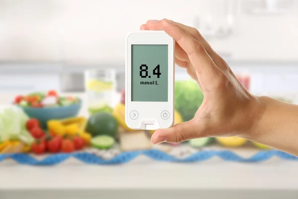 Männliche Hand hält Glukometer mit frischem Obst und Gemüse auf dem Tisch. Diabetes-Konzept — Stockfoto