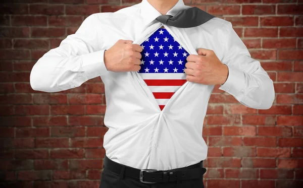 Businessman showing USA flag under suit on brick wall background. — Stockfoto