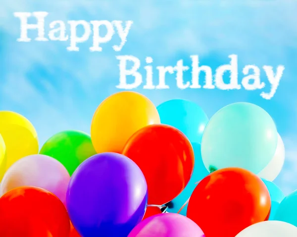 Texto de aniversário feliz e balões coloridos no fundo do céu azul — Fotografia de Stock
