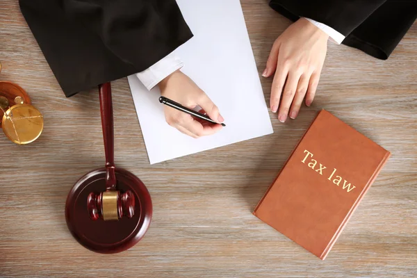 Juez escribiendo sobre papel con mazo en mesa de madera, vista superior. Concepto de Derecho fiscal —  Fotos de Stock
