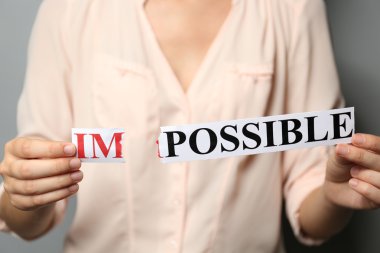 Woman holding word IMPOSSIBLE, close up clipart