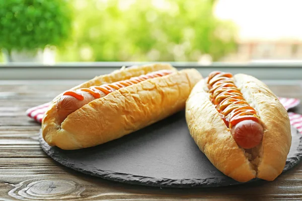 Tasty hot dogs on round wooden board — Stock Photo, Image