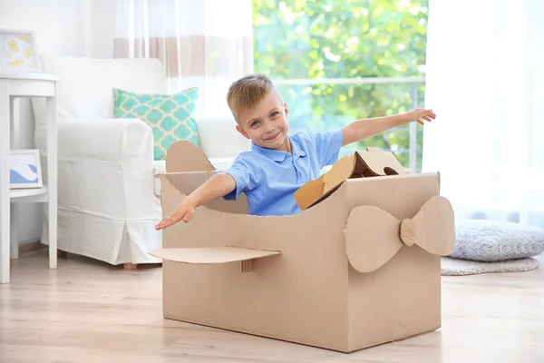 Kleine jongen spelen met kartonnen vliegtuig binnenshuis — Stockfoto