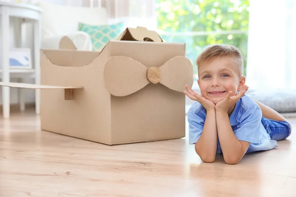 Kleine jongen spelen met kartonnen vliegtuig binnenshuis — Stockfoto