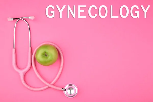Гинекологическая концепция. Стетоскоп с яблоком на цветном фоне — стоковое фото