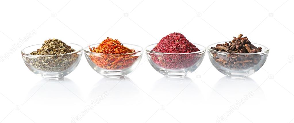 Glass bowls with different spices in a row on white background