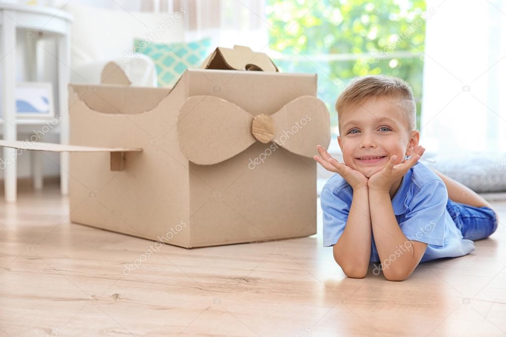 Little boy playing with cardboard airplane indoors