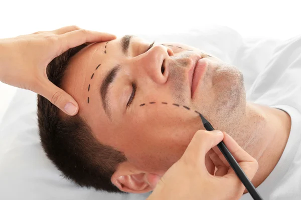 Koncepcja chirurgii plastycznej. Ręce oznakowanie męskiej twarzy — Zdjęcie stockowe