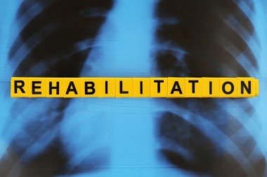Word REHABILITATION made of alphabet blocks on X-ray image background clipart