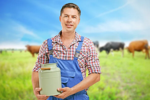 Przystojny mleczarz z można na niewyraźne krowa pastwisko tła. Koncepcja produktu mleczarskiego. — Zdjęcie stockowe