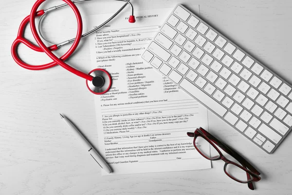 Bureau du médecin avec rapport médical, clavier et stéthoscope — Photo