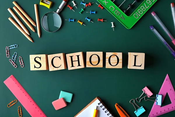 Papelería colorida y palabra ESCUELA en pizarra — Foto de Stock