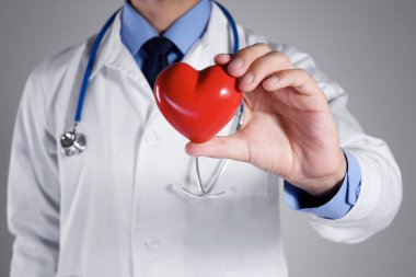 Kırmızı kalp gri arka plan üzerinde closeup tutan erkek doktor