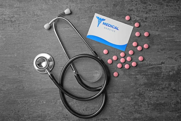 Medicinska begrepp. Stetoskop, visitkort och piller på grå bakgrund — Stockfoto