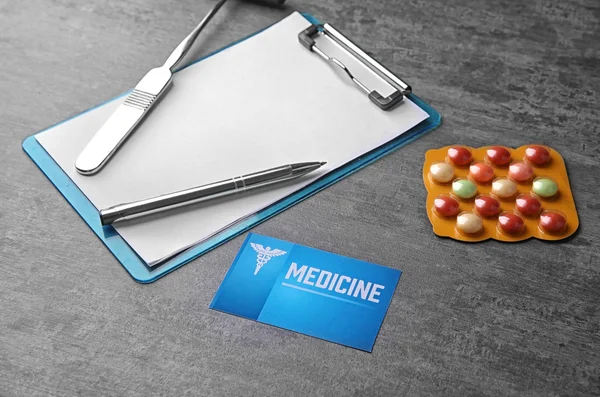 Orvosi koncepció. Vágólap kalapáccsal, tabletták és névjegykártya szürke háttér — Stock Fotó