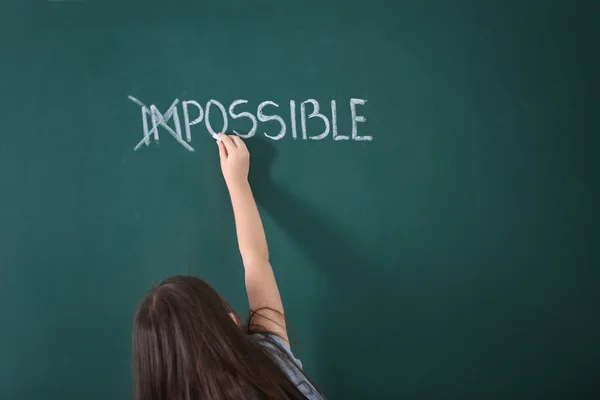 Little girl transforming word on chalkboard — Stock Photo, Image