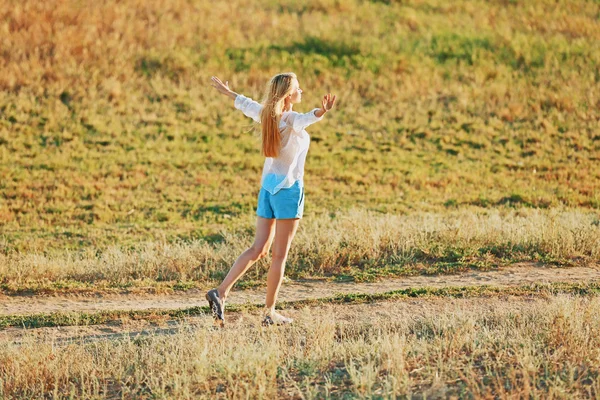 Młoda kobieta spaceru na tle pola — Zdjęcie stockowe