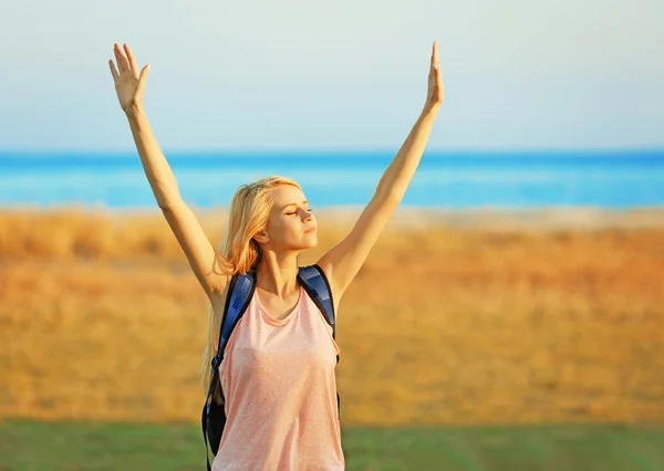 Fiatal nő, emeli a kezét a kék ég háttér — Stock Fotó