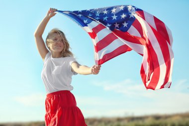 Amerikan bayrağı mavi gökyüzü arka plan üzerinde tutan genç kadın