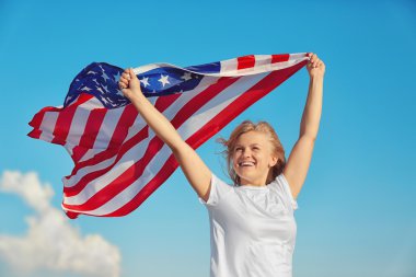 Amerikan bayrağı mavi gökyüzü arka plan üzerinde tutan genç kadın