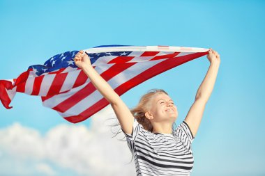 Amerikan bayrağı mavi gökyüzü arka plan üzerinde tutan genç kadın