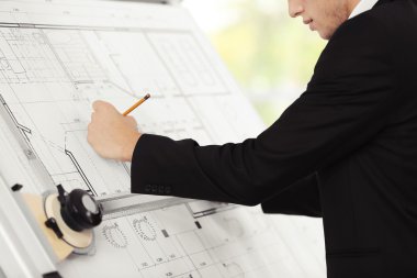 Genç yaratıcı erkek mühendis projesi çizim tahtasında yapmak