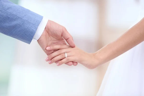 Bride and groom holding hands together indoor — Stock Photo, Image