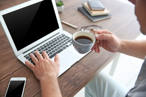Mann arbeitet am Laptop und trinkt Kaffee — Stockfoto