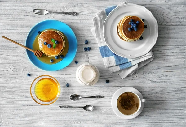 Leckere Pfannkuchen mit Blaubeeren, Minze und Honig auf dem Tisch — Stockfoto