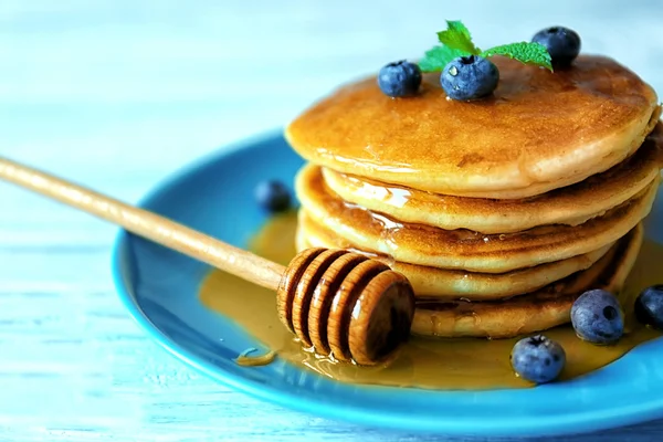 Leckere Pfannkuchen mit Blaubeeren, Minze und Honig auf dem Tisch — Stockfoto