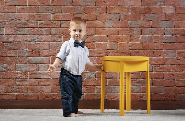 Stylish Little Gentleman Bow Tie Standing Yellow Table Brick Wall — Stock Photo, Image