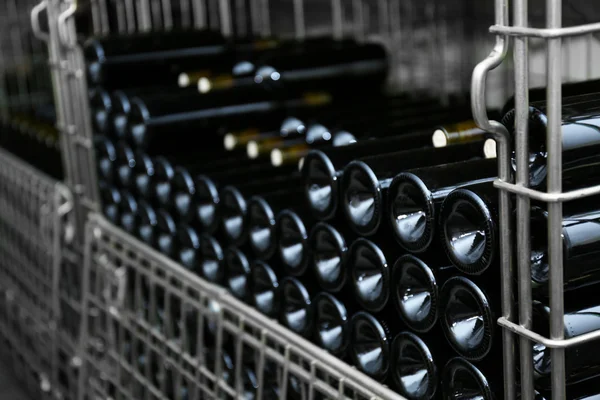 Flessen met wijn op planken in kelder — Stockfoto