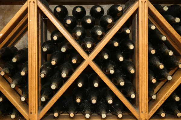 Botellas con vino en estantes de madera en bodega — Foto de Stock
