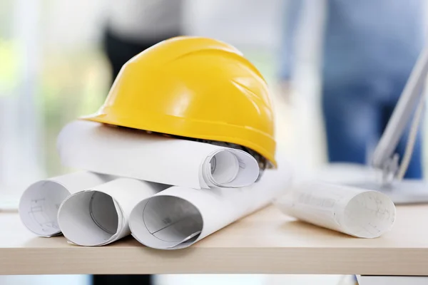 Helm met blauwdrukken op tafel — Stockfoto