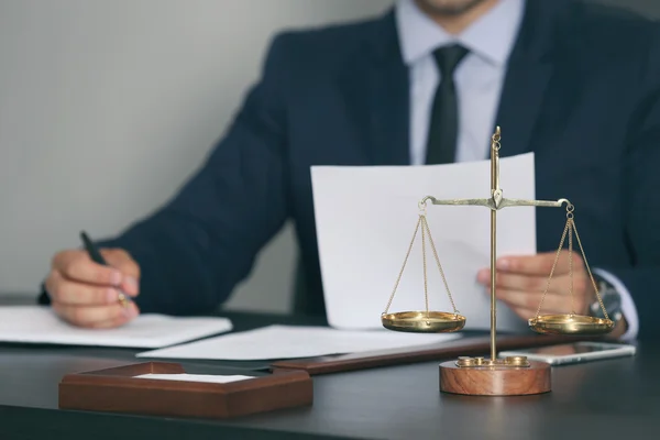 Schalen van Justitie en zakenman zittend aan tafel — Stockfoto