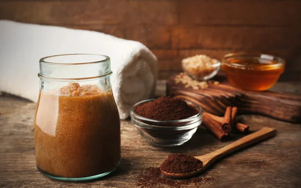 Body scrub and coffee on wooden table