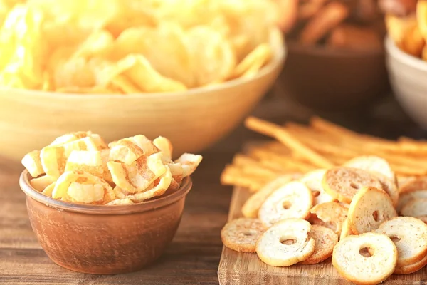 Snack gustosi e bottiglie con birra sul tavolo della cucina sullo sfondo della TV offuscata — Foto Stock