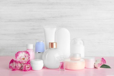 Farklı Kozmetik Şişeler ve gri duvar arka plan üzerinde çiçekler