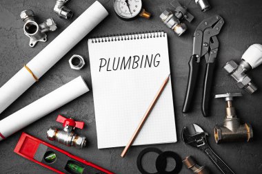 Sıhhi tesisat kavramı. Beton yapı arka plan üzerinde planları ile defter ve tesisatçı araçları