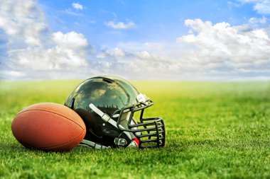 Top yeşil çimen ve mavi gökyüzü arka plan ile Rugby kask