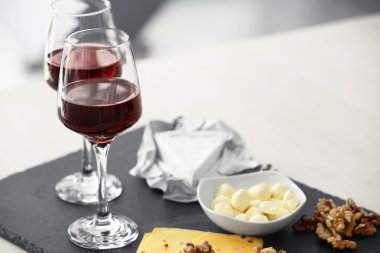 Gözlük kırmızı şarap ve bir tahta üzerinde lezzetli peynir ile