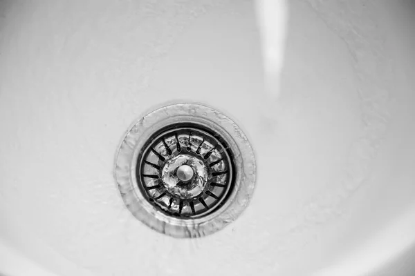 Vatten som rinner i avloppet på diskbänk — Stockfoto