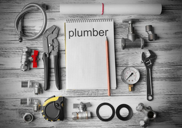 Plumbing concept. Plumber tools with notebook on wooden textured background — Φωτογραφία Αρχείου