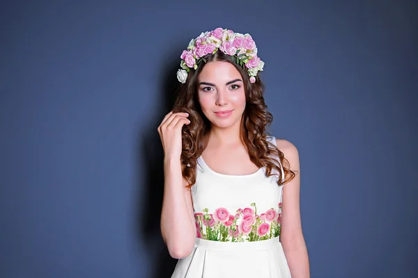 Молода жінка в сукні з красивим квітковим принтом і позує на кольоровому фоні . — стокове фото